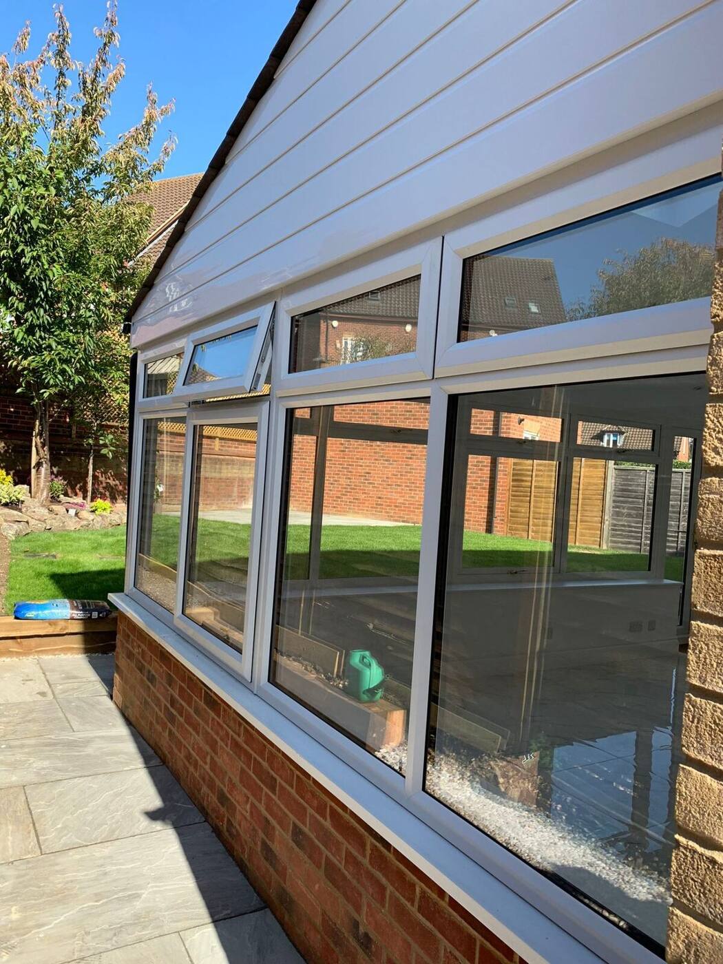 Wide angle view of professionally cleaned conservatory with spotless glass and white UPVC frames