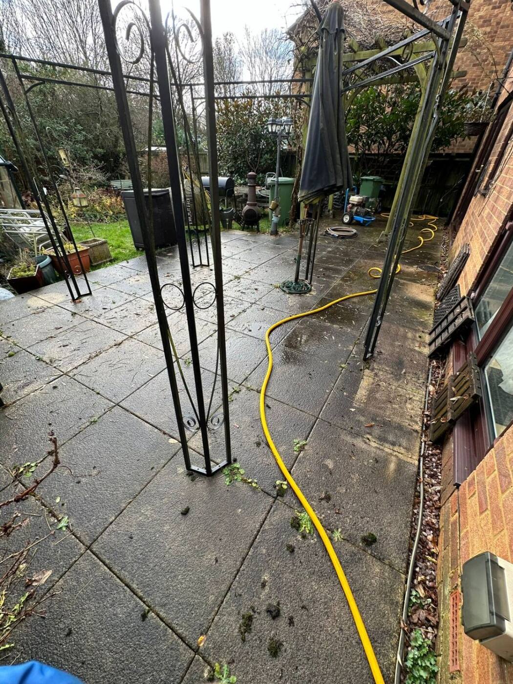 Green algae and moss covered patio tiles with gazebo before pressure washing