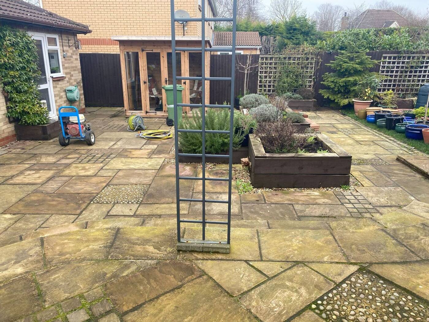 Dirty green-stained Indian sandstone patio before pressure washing